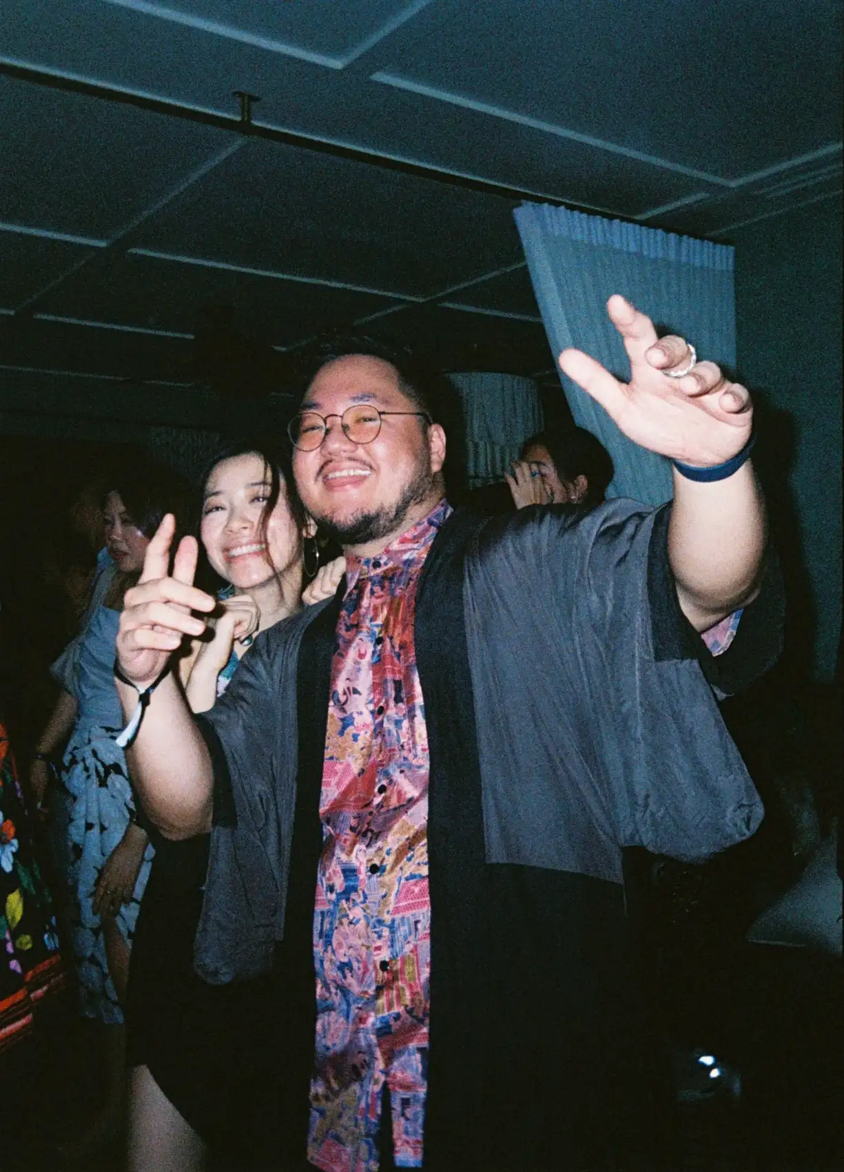 A man in a haori with a woman behind him, both smiling